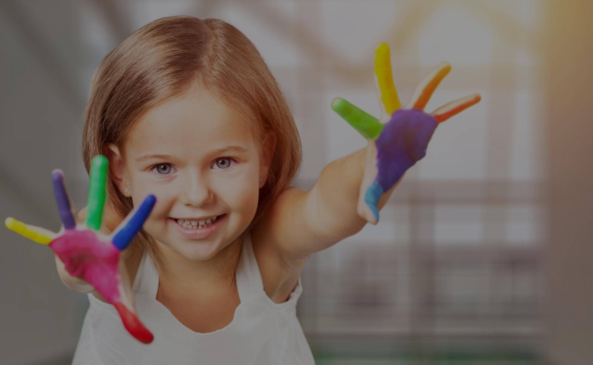 A happy young child with brightly painted hands